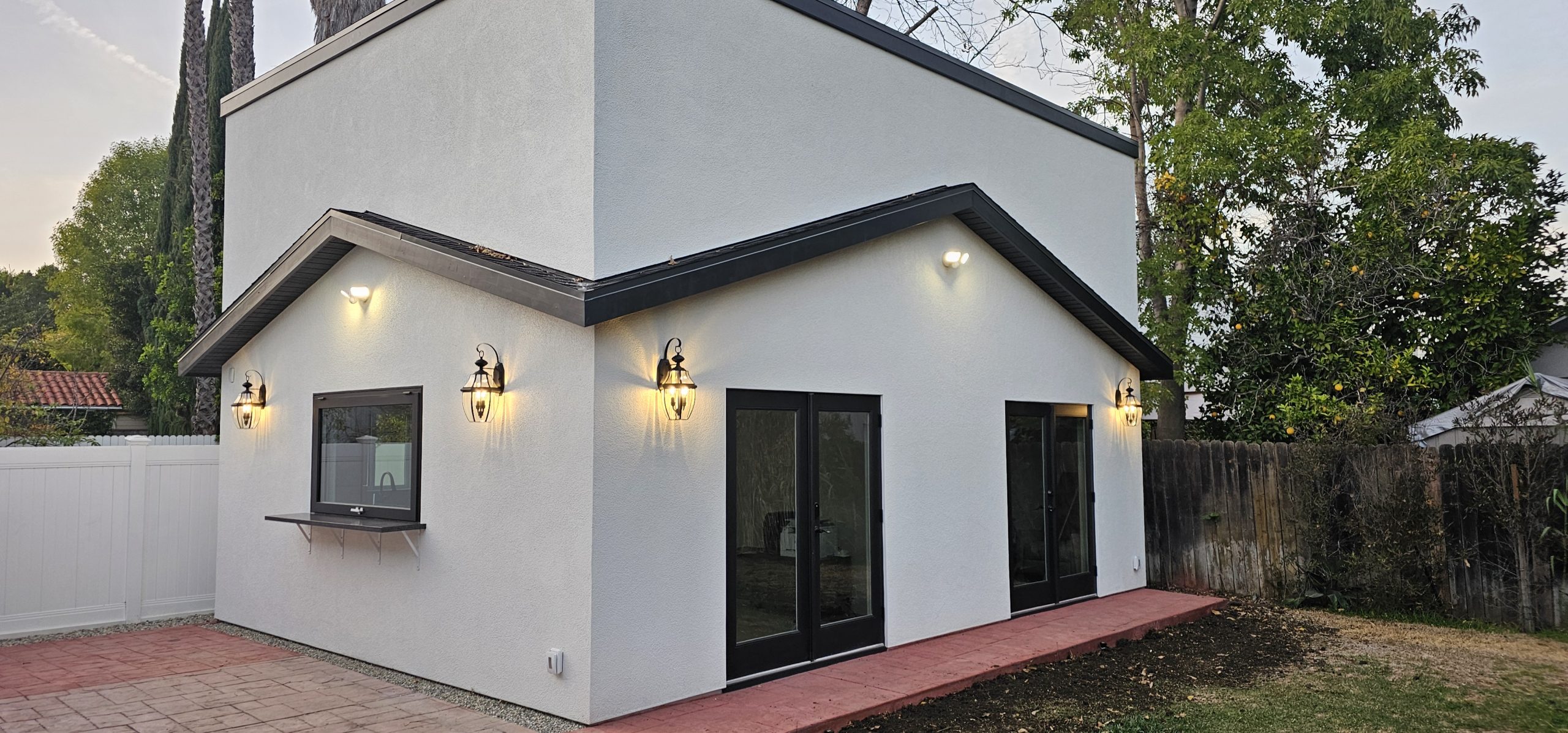 Finished two-story guest house with French doors and exterior lighting