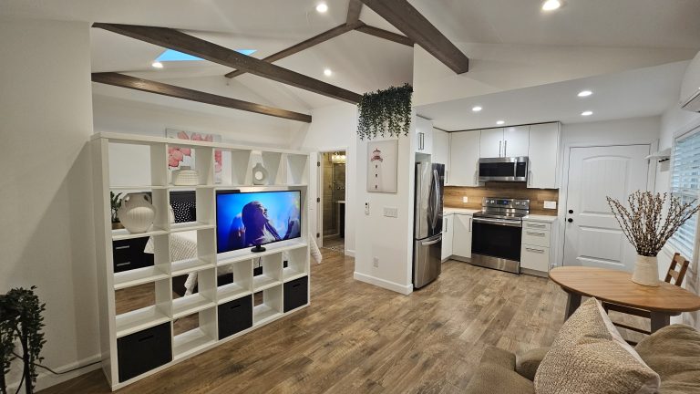 Open living area and kitchen in a finished ADU with wood ceiling beams and skylight by Idea Fix Construction