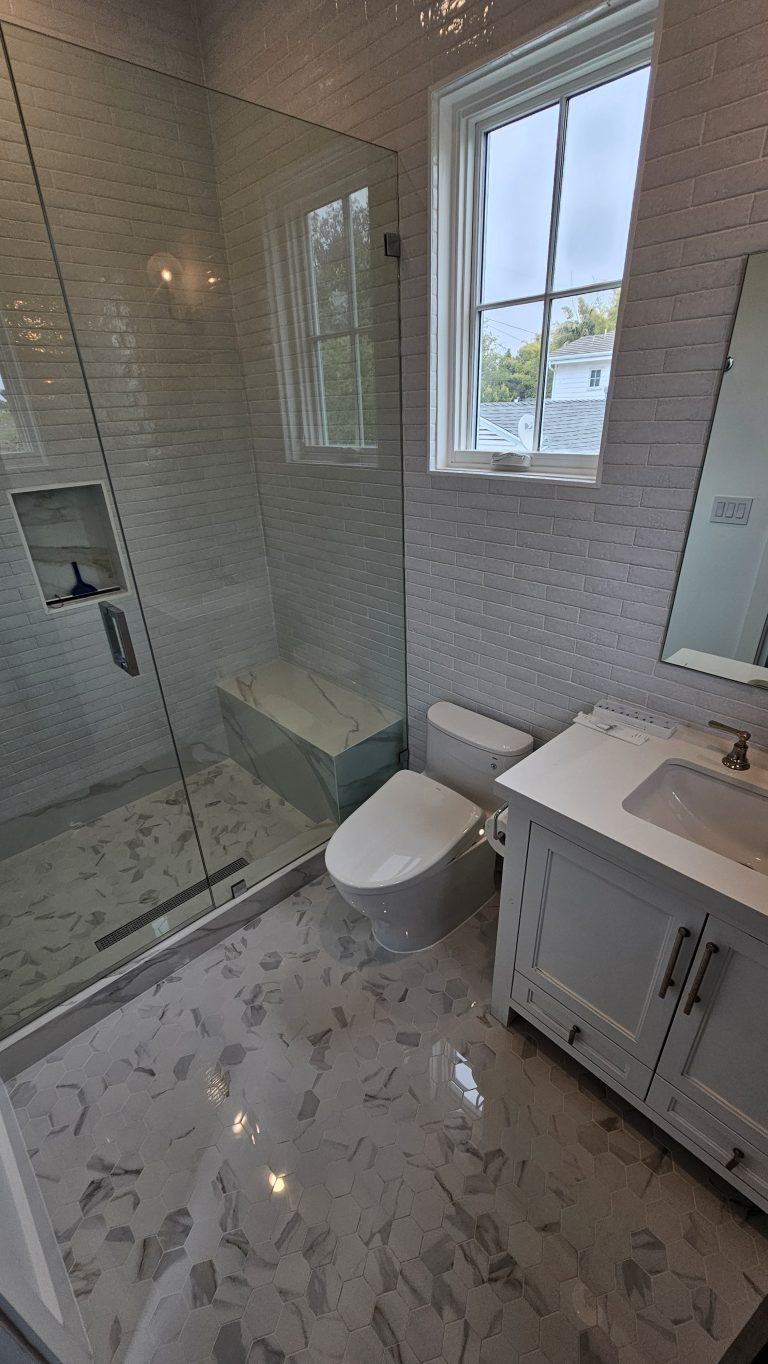 Bathroom with marble hex tile floor, glass shower and white vanity by Idea Fix Construction