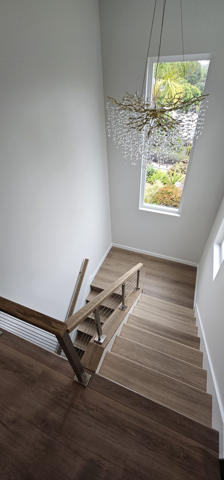 Staircase with large window bringing natural light into a remodeled home by Idea Fix Construction